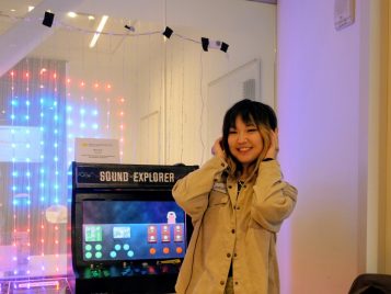 Mya Kim standing by her project, "Arcade cabinet-shaped interactive exhibits from the 8-Bit Music Experience."